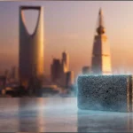 بلكة بركانية على سطح عاكس أمام أفق مدينة الرياض وقت الغروب.